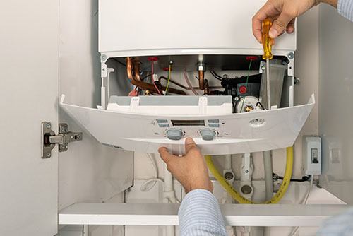 Heating technician repairing a residential boiler in San Dimas