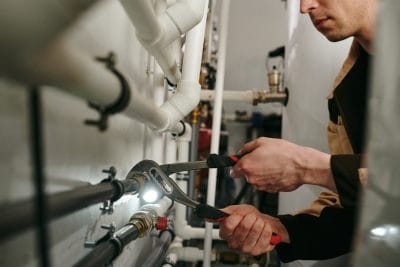 Technician inspecting commercial plumbing pipes in San Dimas