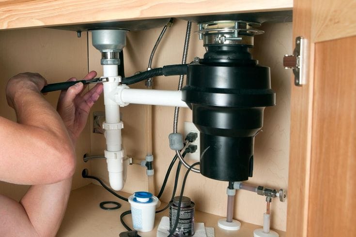 Plumber repairing a garbage disposal in San Dimas