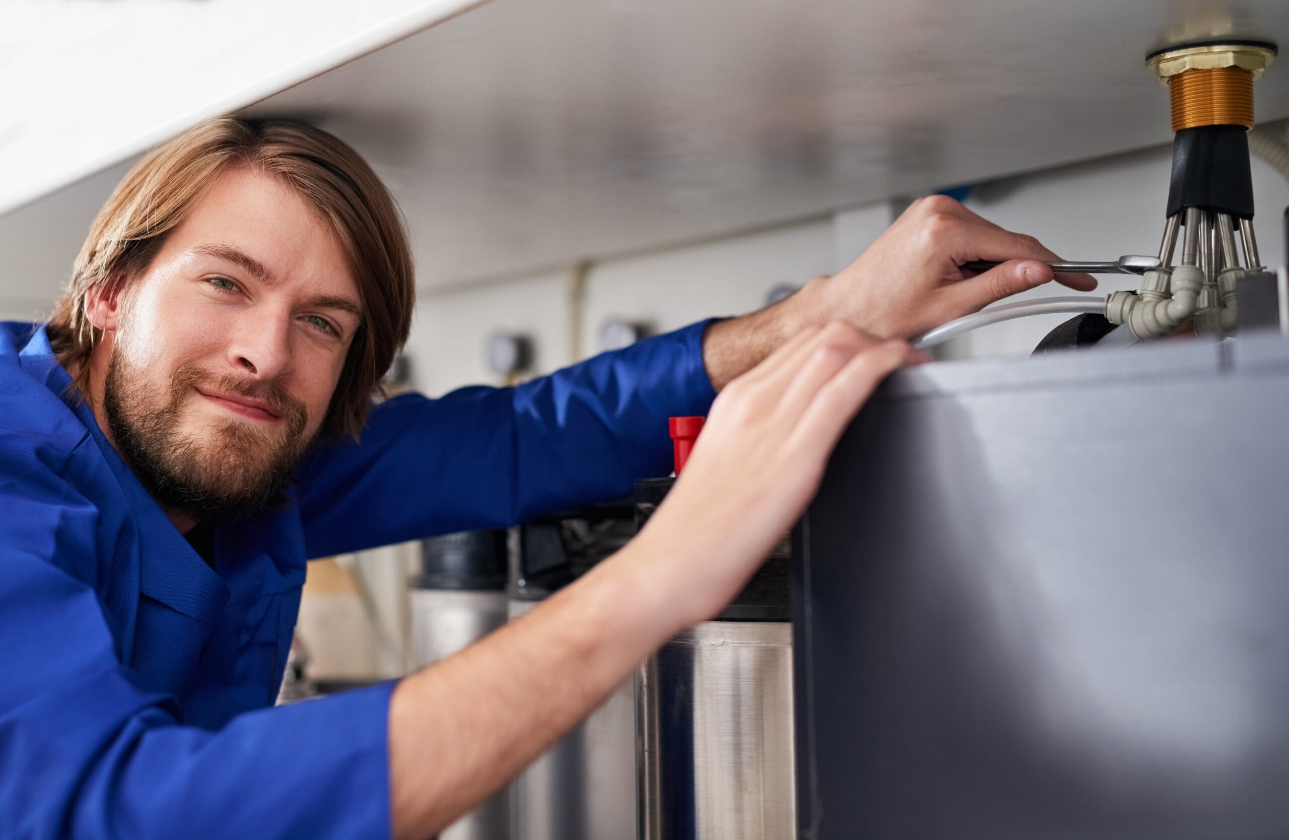 Technician servicing a residential water heater tank in San Dimas